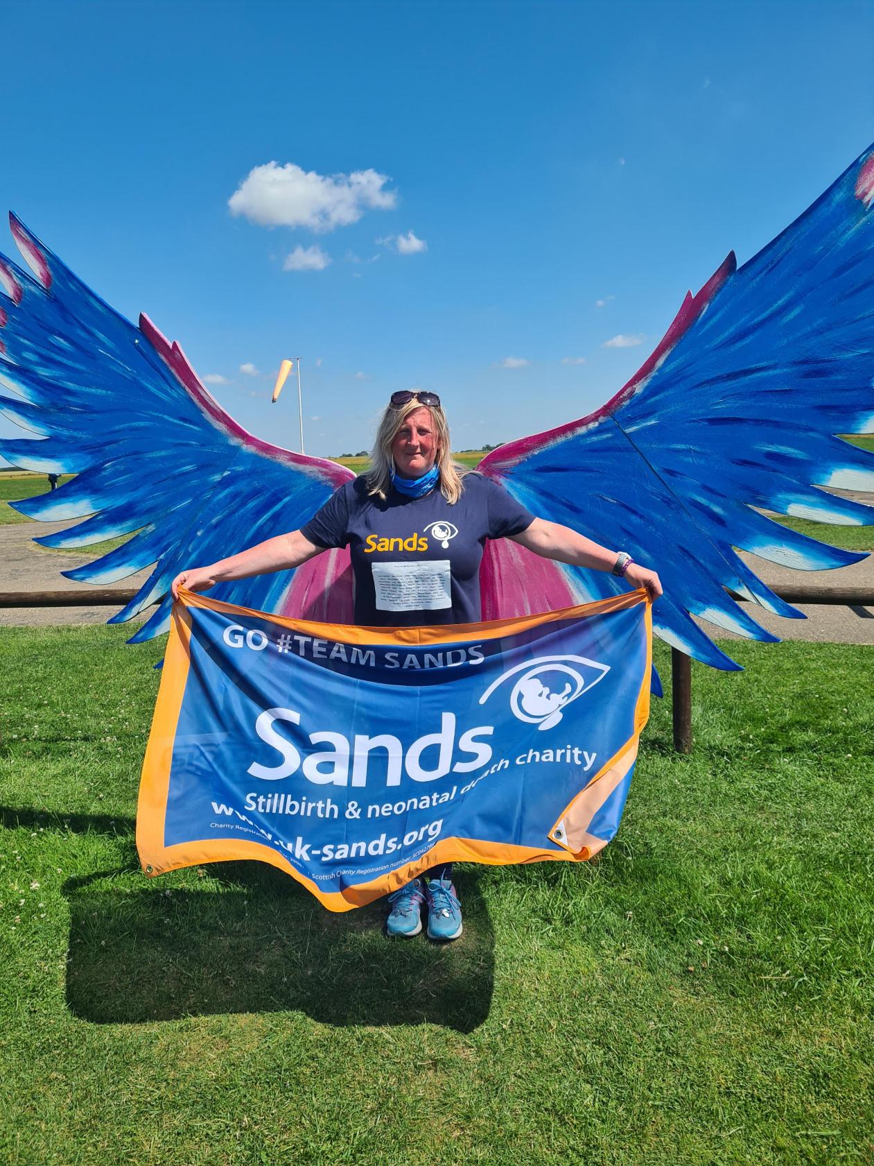 Person holding Sands flag in front of wings