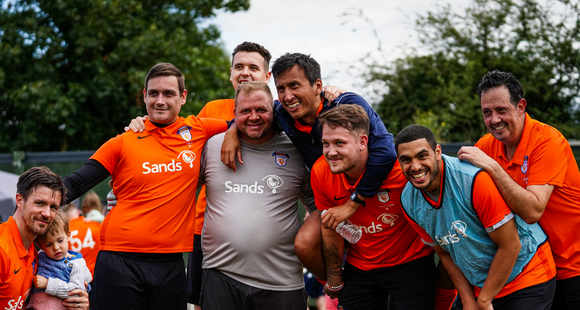 A group of Sands United players in a huddle celebrating a match win.