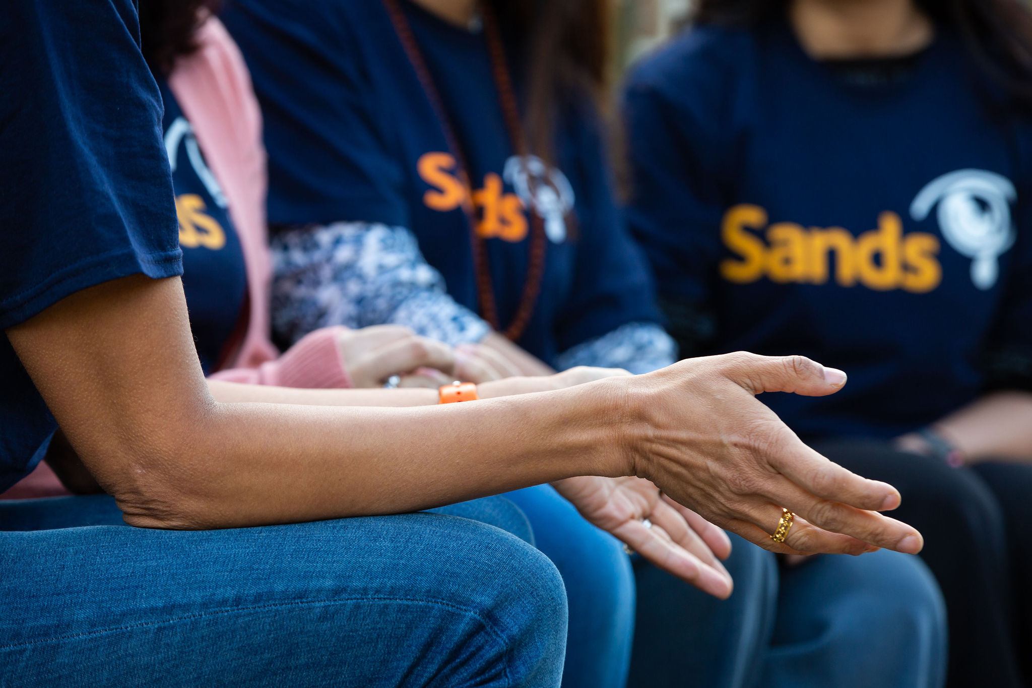 Ladies sat together outside in Sands t-shirts