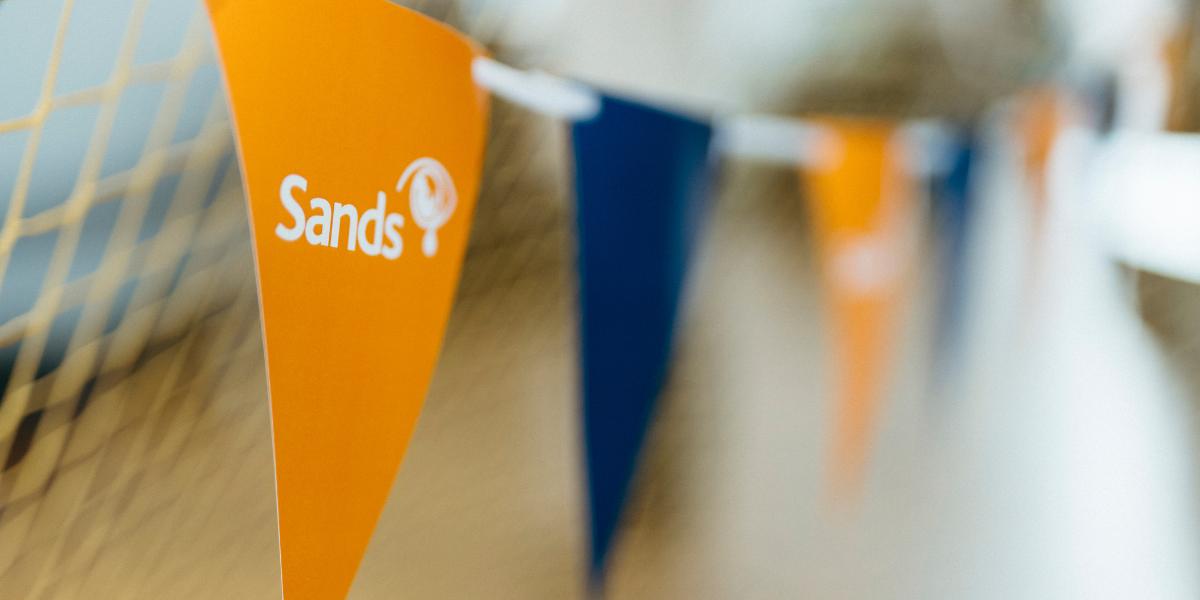 a string of orange and blue bunting with the Sands logo visible on the first orange flag in focus