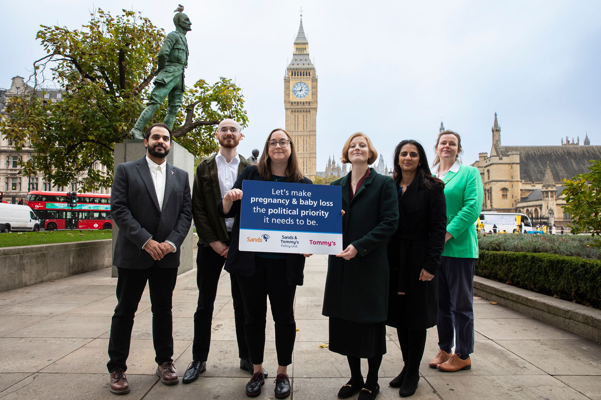 A group of people gathered near Parliament holding a sign calling for pregnancy and baby loss to be a political priority.