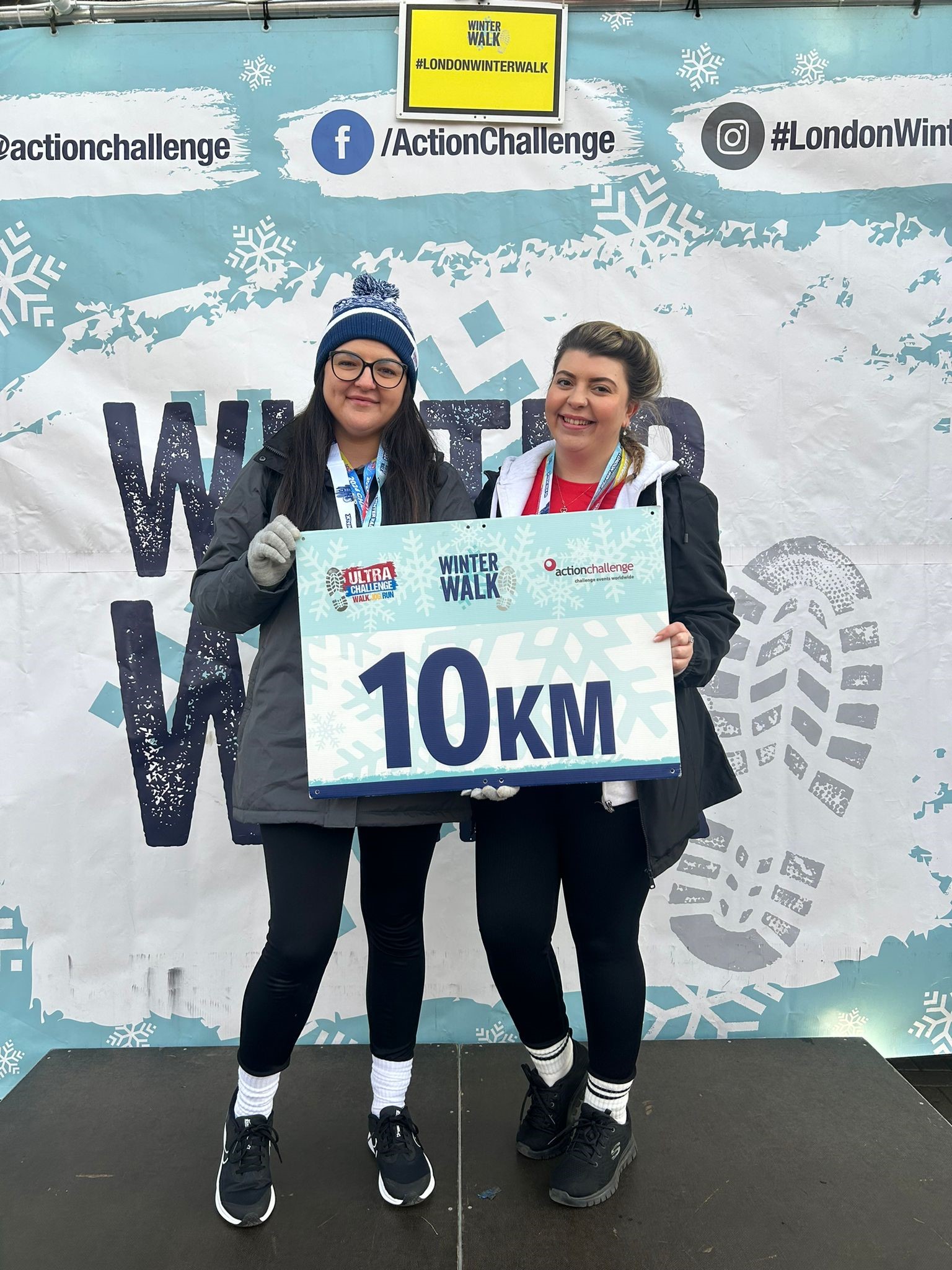 Two Winter Walker holding a Winter Walk Sign.