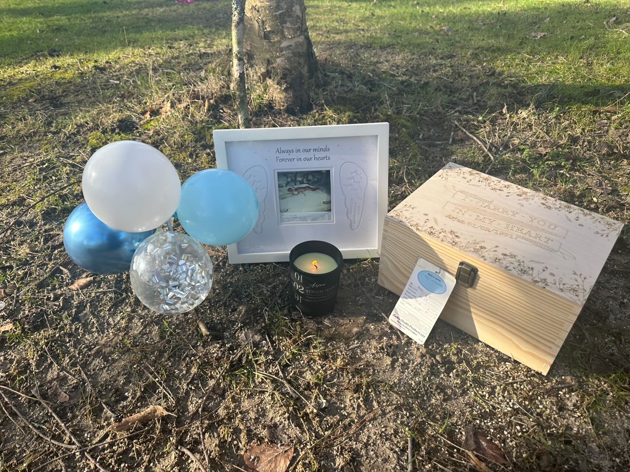 Image of the location where Arjan's ashes are scattered and remembrance items including a photo of Arjan and candle by a tree