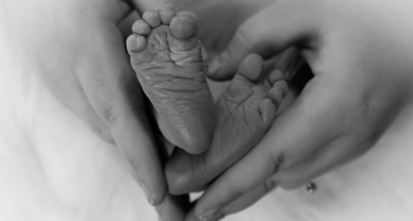 Newborn feet held by adult hands 