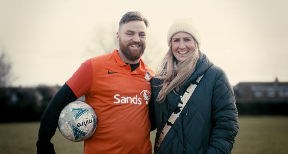 Rob Allen wears a Sands United kit and stands next to his wife Charlotte