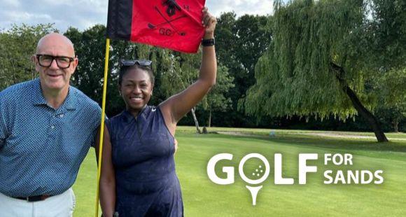 2 people standing along side a golf flag on the golf course 
