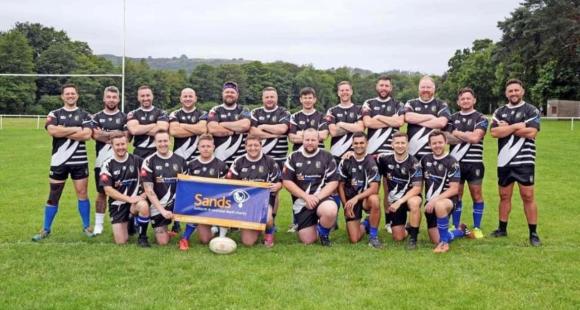 photo of rugby team holding sands banner