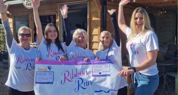 five women holding a Ribbon Run poster