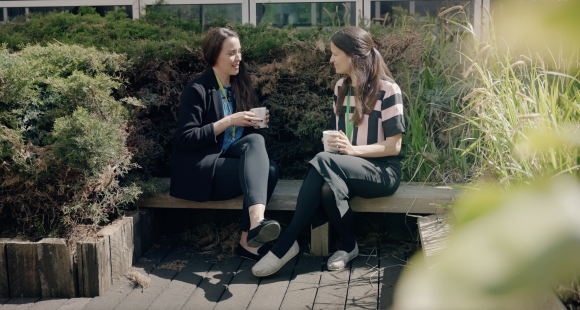 Image of two ladies sat outside on a bench talking