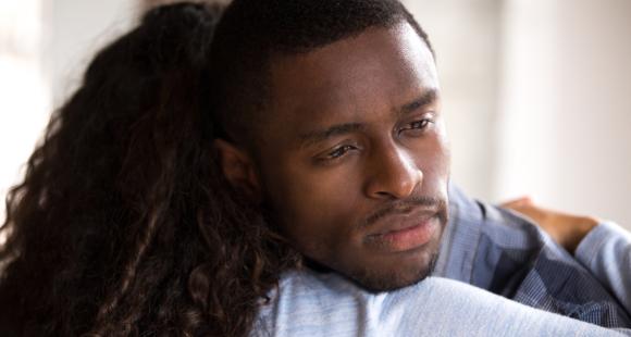 An image of a Black man is being comforted by a Black lady