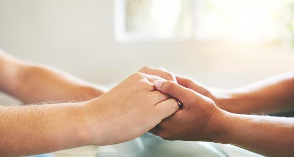 An image of two pair of hands coming together and being held