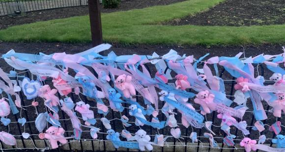blue and pink ribbons and bears tied to fence
