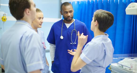 A group of healthcare professionals stand together talking. They