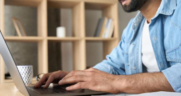 A man sat at a laptop scrolling