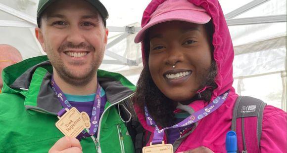 A couple stood holding their Trek Together medals and smiling