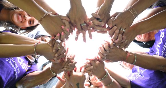 Photo of ladies stood together in a circle and holding hands
