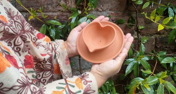 A lady holding a heart-shaped diya