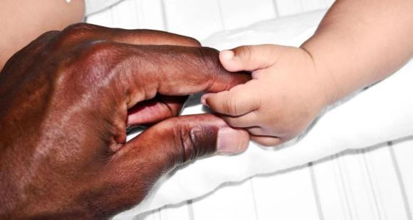 Adult hand holding a baby's hand
