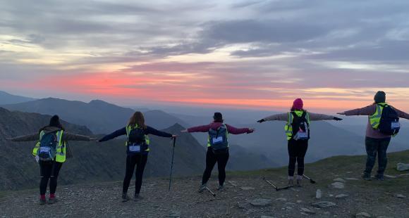 Group of people, arms out, sunset in the background