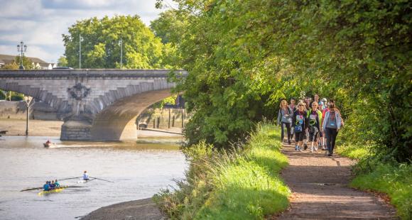 A river and bridge with people walking on a path.