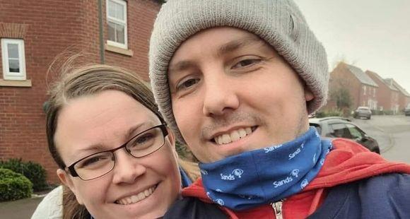 Lady with glasses resting her head on a man's shoulder wearing a Sands t-shirt and a grey beanie hat
