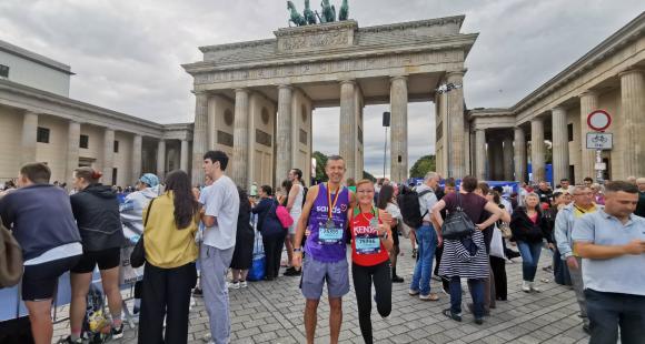 Man and woman standing in front of the brandenburg gate with a crowd of people
