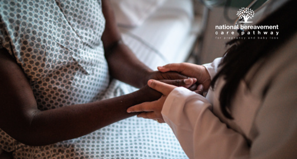 A health professional holds the hands of a black female patient