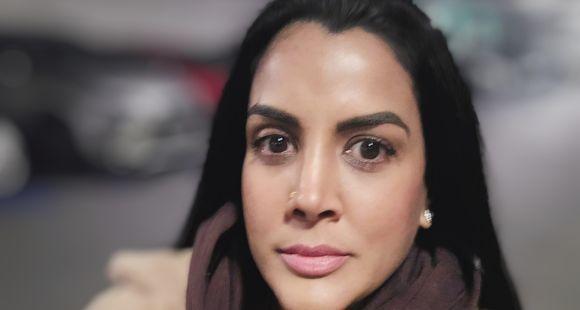 A lady with long dark hair and dark eyes in a brown fluffy coat looks at the camera after talking about her experience of multiple baby loss