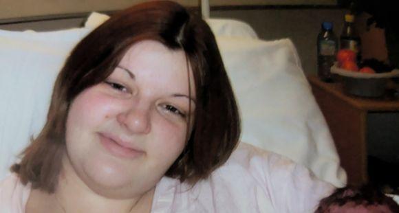 A lady with long brown hair smiles at the camera holding a baby with dark hair