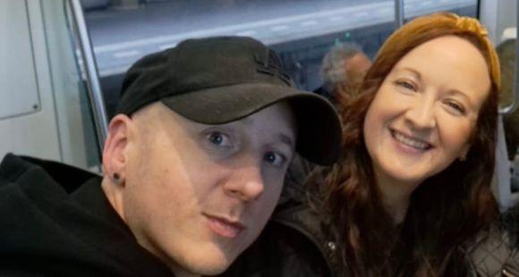 A man wearing a black cap and a lady with auburn hair smiling at the camera together after a lack of support after baby loss.