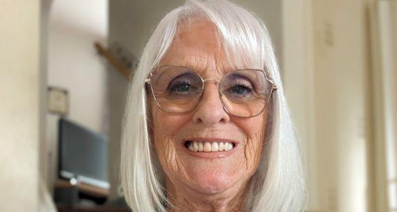 A lady with grey hair and glasses smiles at the camera after remembering her son who passed away at six months old.