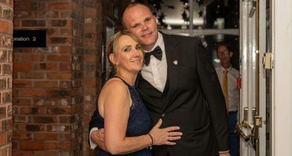 A man and a woman dressed up smile at the camera after sharing how their son died following neonatal care.