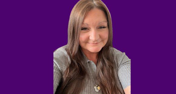 A lady with long brown hair smiles at the camera after sharing failings in maternity care.