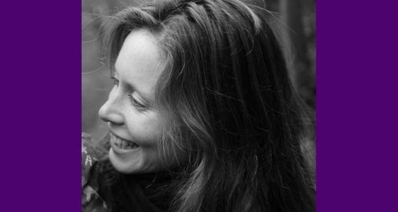 A lady in a grey picture looking sideways and smiling