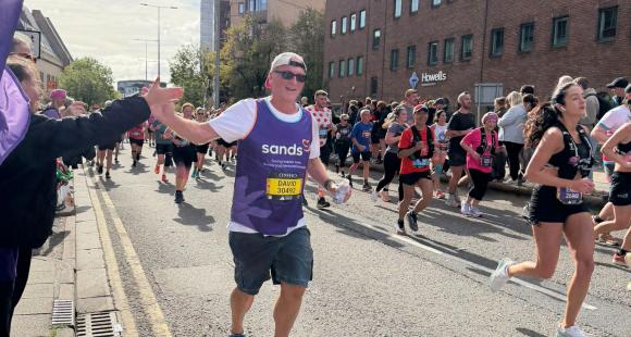 A road with people running, a man running and high fiving crowd