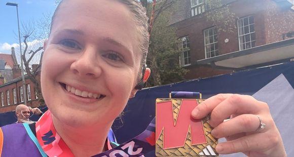 A female runner holding up a medal