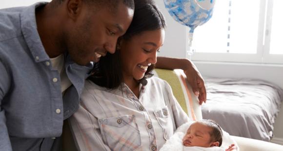 Black mum and dad smile at their baby