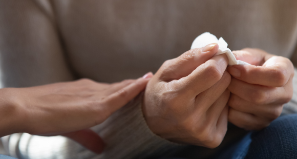 Close up of someone's hands holding a tissue, and someone else reaching out in support.