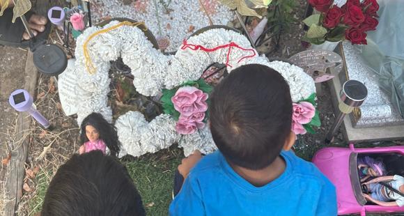 Two boys placing a yellow and red rakhi on their sisters resting place