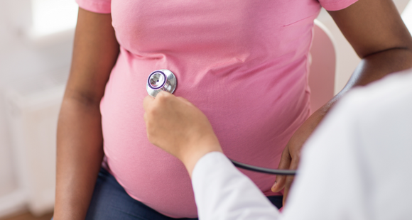 Pregnant woman in pink top is examined by doctor