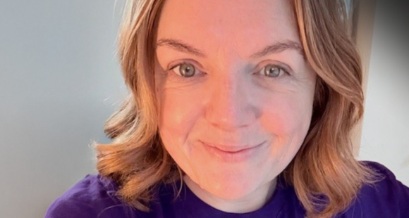 Ruth smiling wearing a purple Sands branded t shirt