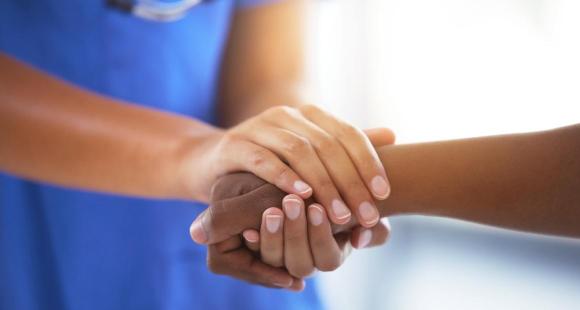 A nurse holds a woman's hand