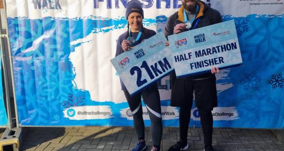 Two sands participants holding up a finishers sign