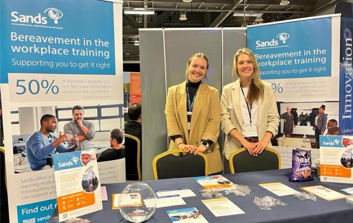 Sands staff stand at an expo with Beareavement in the Work Place Training banners