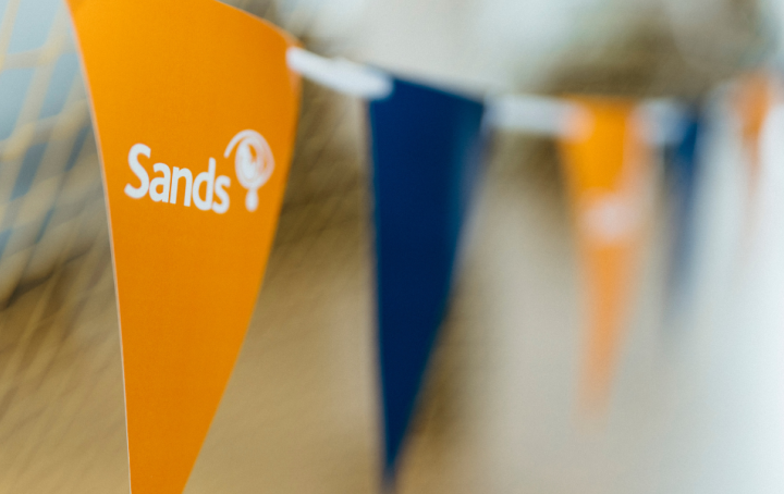 a string of orange and blue bunting with the Sands logo visible on the first orange flag in focus