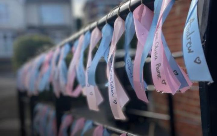 A selection of pink and blue ribbons tied to a railing