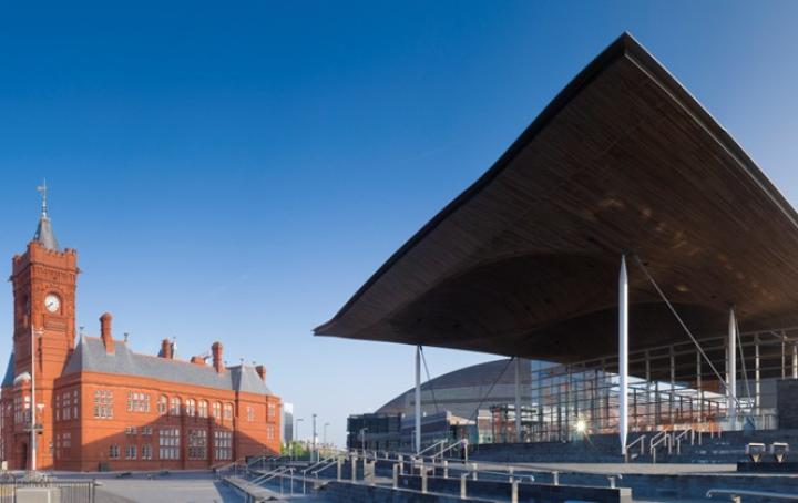 A tall glass building, with a set of stone stairs leading to the entrance. To it's left is a brick church building.