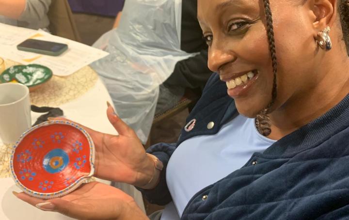 A lady is seen smiling after making a beautiful diya lamp