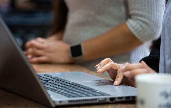 A lady's finger is moving the mouse trackpad on a laptop
