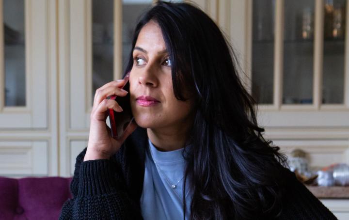 A lady sat at a table speaking to someone on the Sands helpline